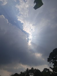 Low angle view of sunlight streaming through clouds