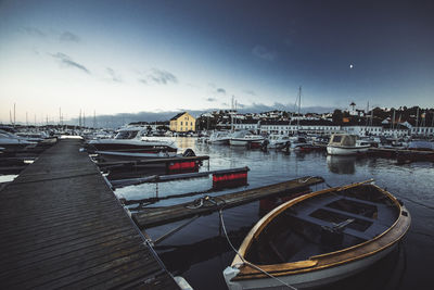 Sailboats moored at harbor against sky