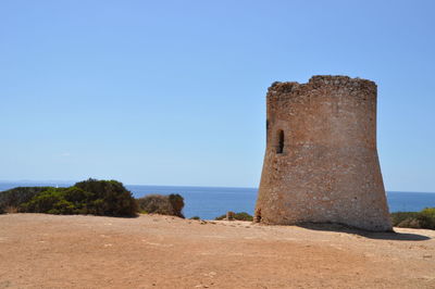 View of ruins at sea against clear blue sky