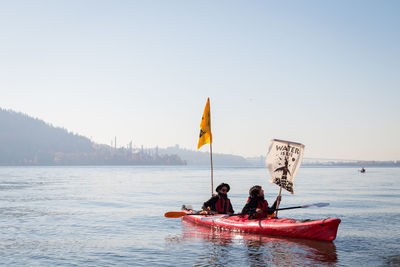 People on boat in sea against clear sky