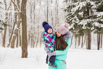 Rear view of woman walking on snow covered field