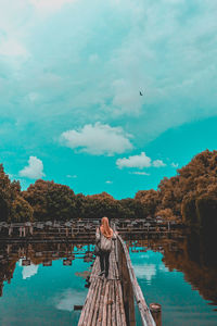 Low angle view of woman standing on riverbank against sky