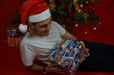 Young man holding christmas present while lying on floor