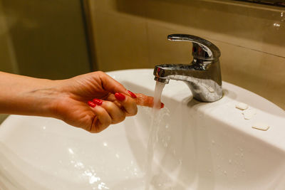 Cropped hand washing hands in sink