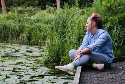 Side view of smiling woman sitting by lake