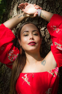 Portrait of smiling young woman with arms raised in park