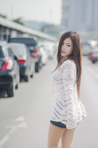 Beautiful young woman standing at parking lot