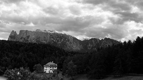 House by trees and mountains against sky