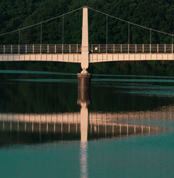 Reflection of bridge over to water pump station at lake in tokyo against blue sky.