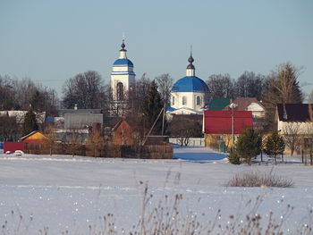 Building by trees against clear sky during winter