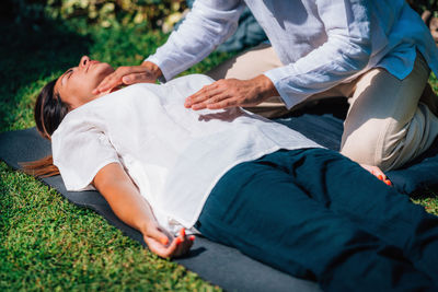 Reiki practitioner healing throat chakra, woman lying with her eyes closed