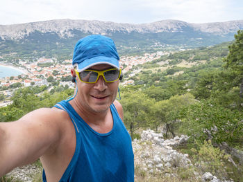 Portrait of smiling man wearing sunglasses against mountains and sky