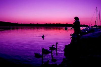 Men working in lake against sky during sunset