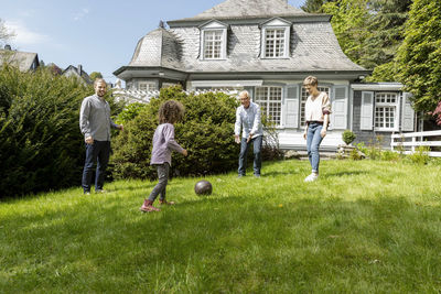 Happy extended family playing football in garden