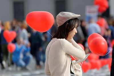 Rear view of woman with balloons standing outdoors