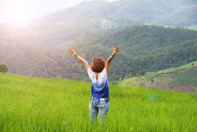 Rear view of woman standing on field against sky