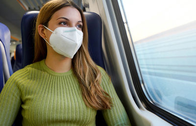 Woman wearing protective face mask ffp2 kn95 on public transport looking through the window