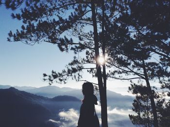 Silhouette woman standing by tree against sky