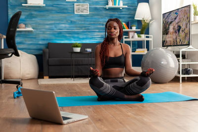 Full length of woman doing yoga at home