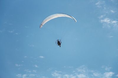 Low angle view of person paragliding against sky
