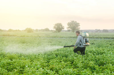 Farmer with a mist sprayer blower processes the potato plantation. protection and care. 