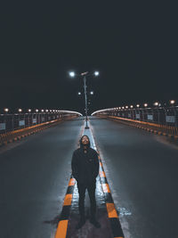Full length of man standing on illuminated road against sky at night