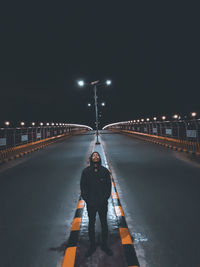 Full length of woman standing on illuminated road against sky at night