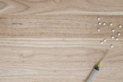 Drug addict with needle with pills on a wooden table. 