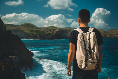 Rear view of man standing by sea against sky