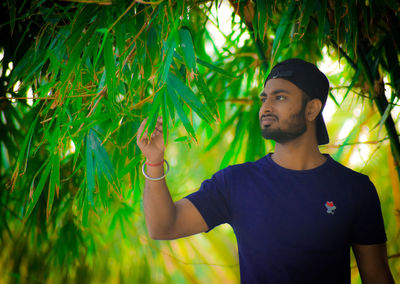 Portrait of young man standing by leaves