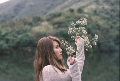 Side view of young woman holding flowers