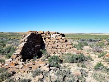 Stone wall on land against clear blue sky