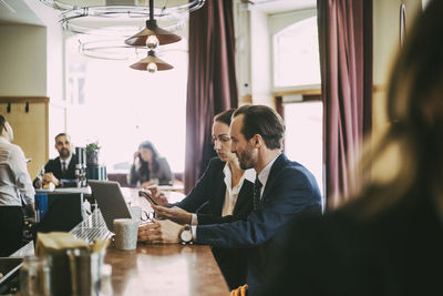 Businesswoman using phone with businessman in restaurant