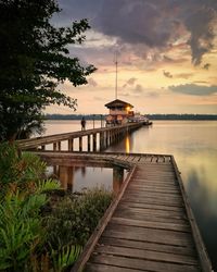 Pier over lake against sky during sunset