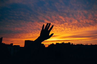 Silhouette hand against sky during sunset