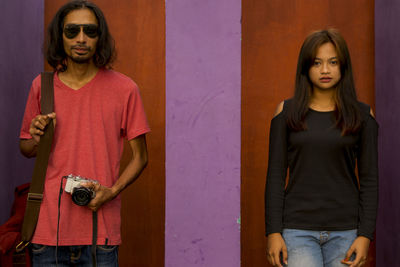 Portrait of young man and woman against wall