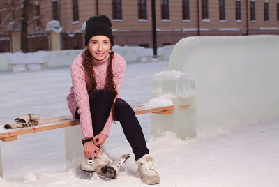 Young pretty woman putting on skates before skating