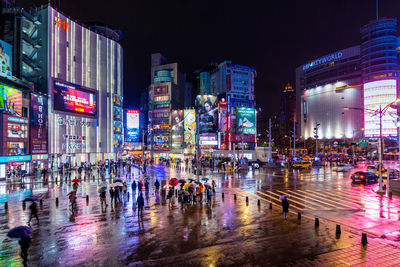 People by illuminated buildings in city at night