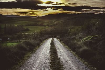 Road leading towards mountains against sky