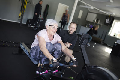 Coach assisting to senior woman exercising in gym