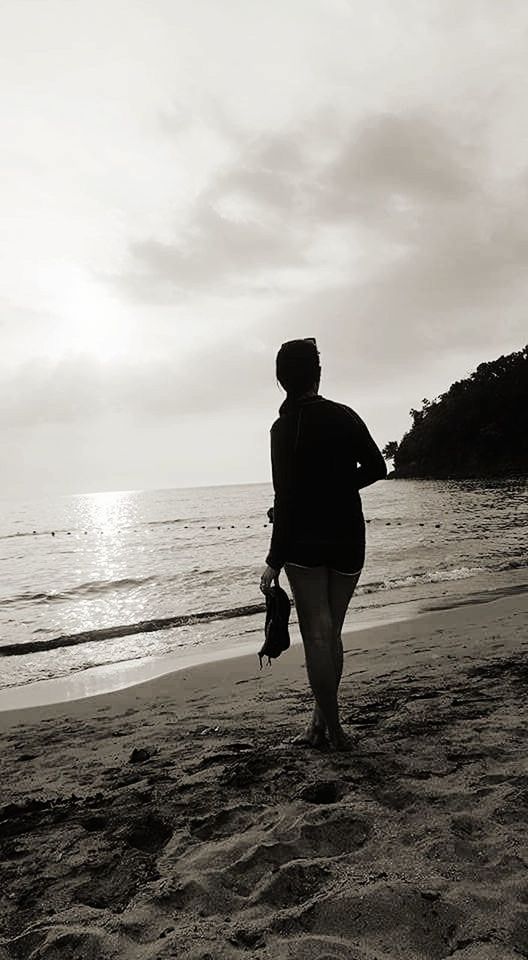 REAR VIEW OF MAN WALKING ON BEACH AGAINST SEA