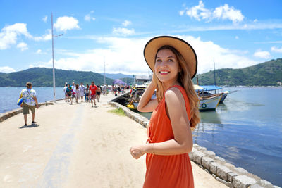 Attractive tourist woman on pier turns around and looking away smiling ready for boat trip