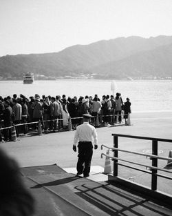 Rear view of people standing by railing against mountain