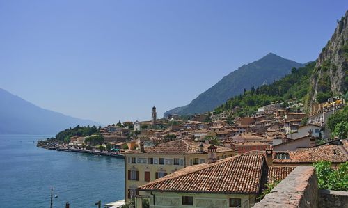 Buildings by sea against clear blue sky