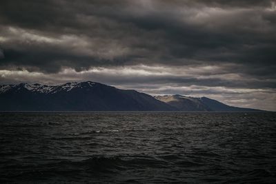 Scenic view of sea against cloudy sky at night