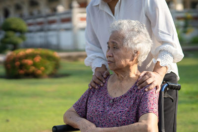 Caregiver help and care asian senior woman patient sitting and happy on wheelchair in park