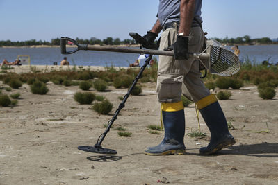 Low section of man standing on land against sky