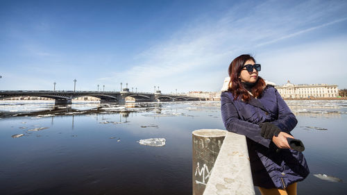 Young woman standing on bridge against sky