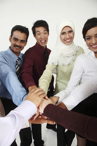 Portrait of colleagues with stacking hands against white background