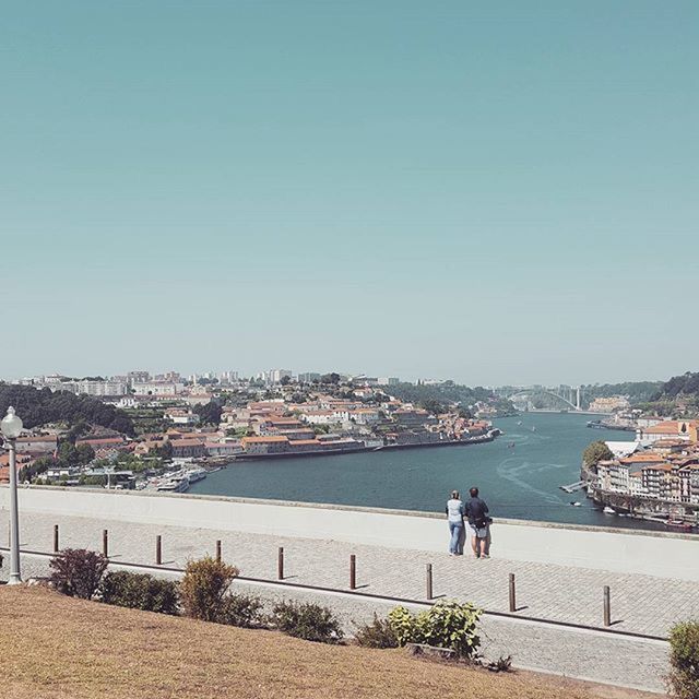 clear sky, water, copy space, building exterior, built structure, architecture, city, river, person, lifestyles, men, leisure activity, railing, city life, walking, blue, sea, day, sky